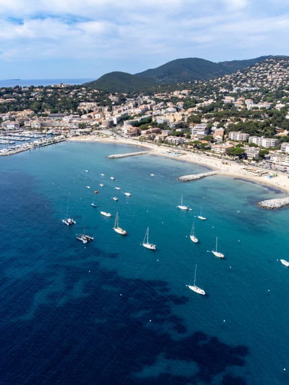 Aerial view on boats, crystal clear blue water of Plage du Debarquement white sandy beach near Cavalaire sur Mer and La Croix Valmer, summer vacation on French Riviera, Var, France